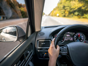 Woman driver's hands on the steering wheel inside the car.